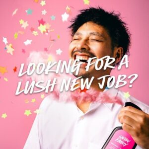 Vor einem rosa Hintergrund besprüht sich ein lachender junger Mann mit dem Snow Fairy Bodyspray. Bunte Sterne regnen von der Decke. Darüber steht der Schriftzug: "Looking for a Lush new job?"
