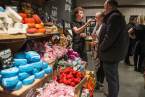 Lush Cribbs Causeway. A Lush colleague shows products to customers on the shop floor.