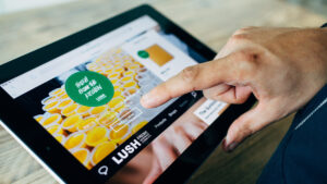 Close-up of a person's hand hovering over and i-Pad with the Lush website on the screen