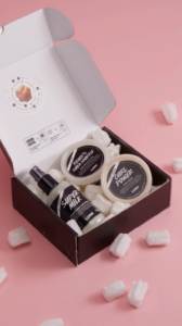 A Lush box containing Super Milk, Renee's Shea Souffle and Curl Power inside, sitting on a pale pink surface