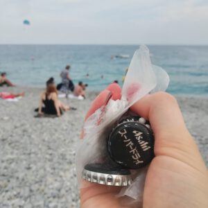 Close up of a person's hand holding bottle caps and plastic on a beach