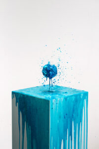 Intergalactic bath bomb splattering in mid air above a block dripping with blue colour