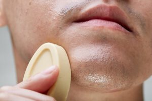 A person applies Banana Skin facial serum to their chin