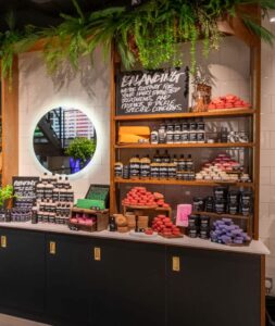 A colourful range of haircare is displayed on a white, black and pine wood unit at Lush Oxford Street. The range includes shampoo and conditioner bars, a solid co-wash, liquid shampoos and conditioners, dry shampoo and hair treatments.