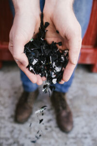 Hands holding a pile of shredded black pot plastic